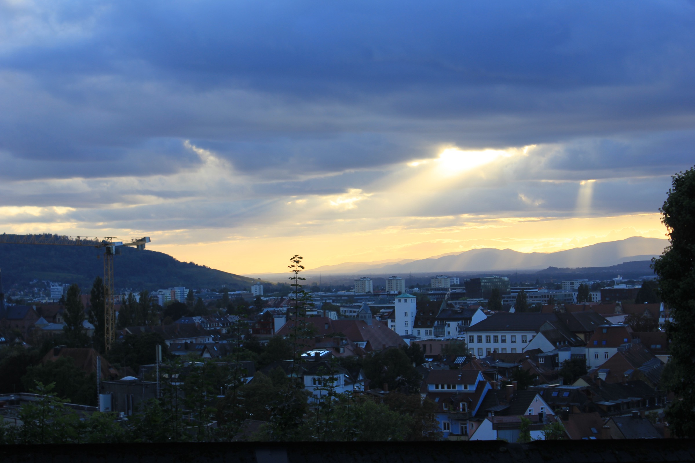 Town skyline at sunset with sun rays through clouds