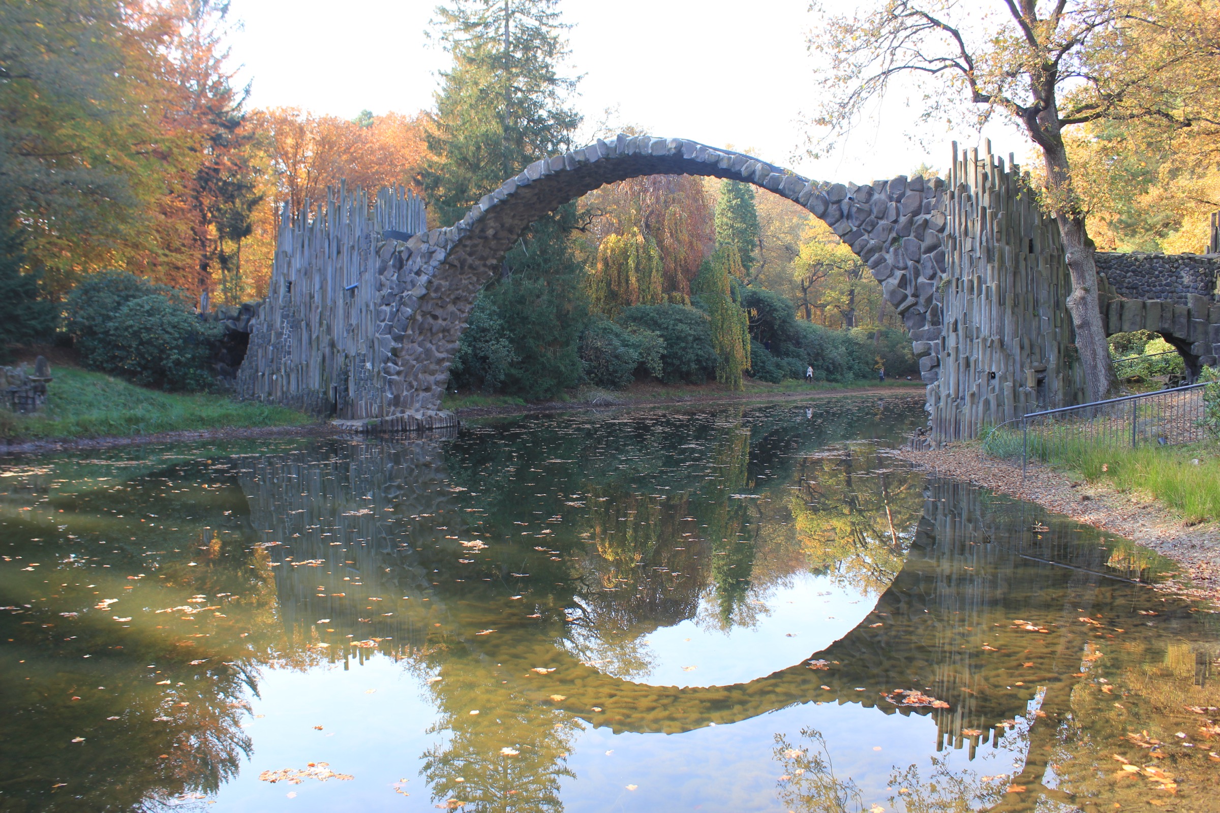 Stone arch bridge reflected in water, autumn